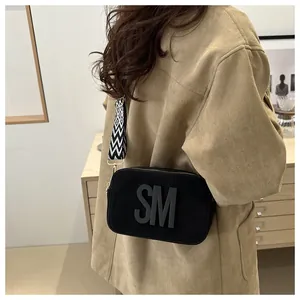 Close-up of black crossbody camera bag with 3D SM logo and geometric woven strap