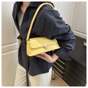 Détail d'un sac sous le bras jaune à motif crocodile avec fermoir tournant argenté