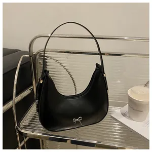 Detail of black leather hobo bag with silver bow ornament on a designer shelf