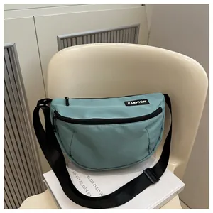 Detail of mint green nylon crossbody bag with fashion label and black adjustable strap