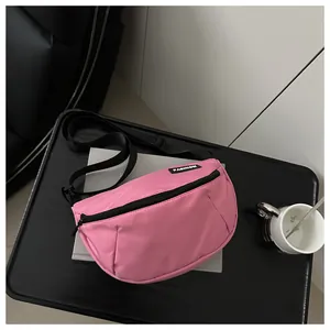 Detail of pink nylon crossbody bag featuring fashion label and adjustable strap