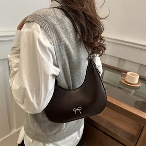 Chic brown hobo shoulder bag with a silver bow detail shown on model in a soft indoor setting