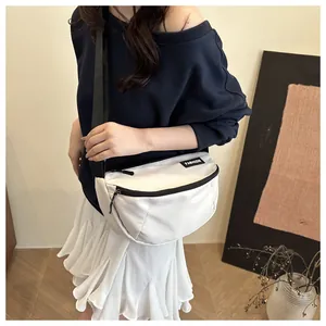Detail of white nylon crescent bag with black zipper and fashion label shown on model