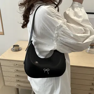 Chic black half-moon hobo bag with silver metal bow detail in a lifestyle setting