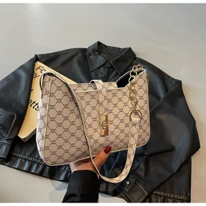 Dettaglio della borsa sottobraccio beige con monogramma e chiusura in metallo dorato