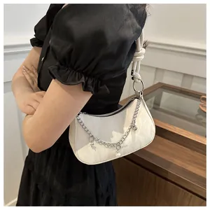 Detail van witte hobo-tas met zilveren bedelketting en schouderband met touwknoop