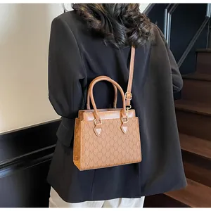 Rear view of a model wearing the brown monogram tote bag with gold hardware detail