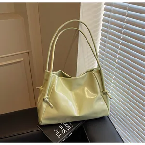 Close-up of light green glossy tote bag featuring slim double straps and side knot details