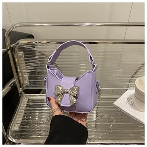 Gros plan du mini sac lavande avec nœud en métal argenté et texture en cuir mat délicat