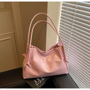 Close-up of pink ruched shoulder bag with leather knots on a stylish leather background