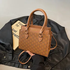 Retro brown tote bag with M-letter monogram print and top handles on leather background