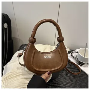 Detail showing brown crescent bag with knotted handle and white FASHION lettering text