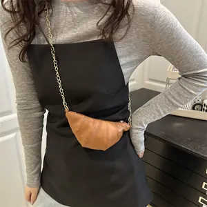 Brown mini croissant crossbody bag with gold chain strap and vertical stitched texture