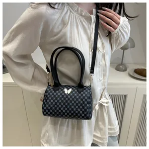 Dettaglio borsa Boston nera con motivi geometrici blu e chiusura a farfalla dorata