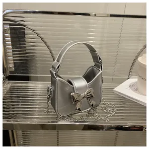 Gros plan d'un mini sac argenté futuriste avec nœud métallique sur étagère ondulée