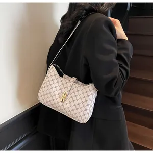Modella che indossa una borsa sottobraccio monogramma bianco con fibbia dorata su blazer