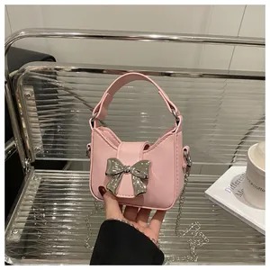 Détail d'un mini sac à main rose avec un nœud métallique argenté et une chaîne