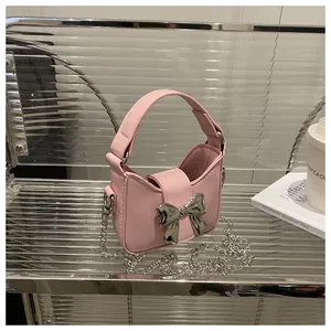 Détail du mini sac rose avec nœud métallique et bandoulière en chaîne argentée