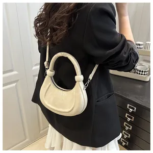Close-up of beige crescent bag with round handle and silver fashion text detail