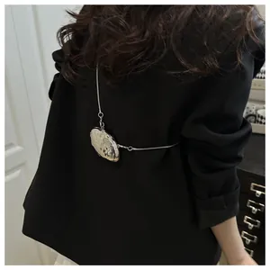 Detail of silver shell-shaped mini bag with snake chain on black blazer jacket back