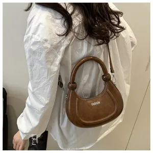 Detailed shot of vintage brown crescent bag with FASHION text worn as crossbody
