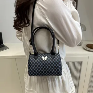 Borsa Boston vintage con motivo geometrico blu e chiusura a farfalla bianca su modella