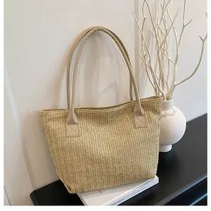 Dettaglio borsa tote in paglia intrecciata con manici in PU su sfondo minimalista