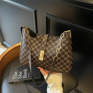 Elegante borsa sottobraccio monogramma con catena dorata su sfondo in legno vintage