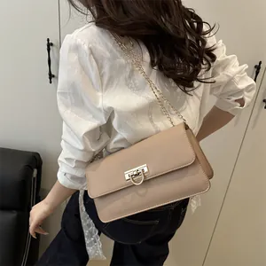 Elegant beige baguette shoulder bag with gold clasp shown on model from the back view