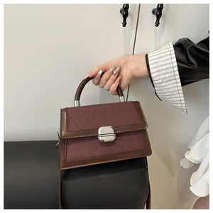 Detail of burgundy woven crossbody bag with brown leather trim and silver metal lock