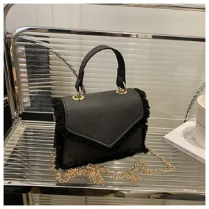 Detail of black bag with fringe edges and elegant gold chain strap on chair