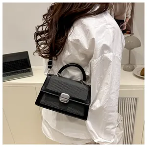 Close-up of minimalist black handbag with silver twist lock on a modern office desk