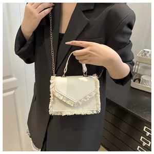 Detail view of a white fringe square bag with synthetic leather texture and gold chain
