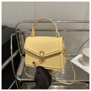 Detail of cream yellow crossbody bag with gold metallic lock and smooth faux leather