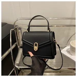 Macro detail of black square crossbody bag showing matte leather texture and gold metal lock