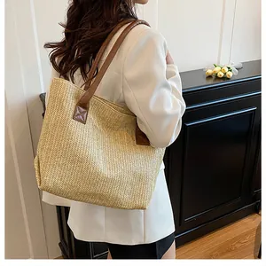 Dettaglio di una borsa tote in paglia intrecciata con manici in pelle marrone e spina