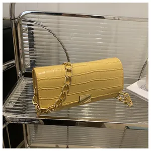 Detail of yellow crocodile texture shoulder bag with chunky gold chain strap and metal buckle