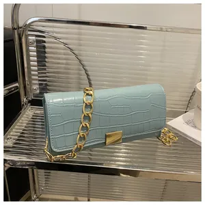 Detail of light blue crocodile texture handbag featuring a chunky gold chain strap