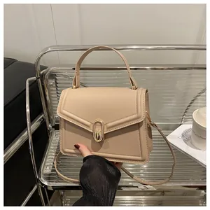 Detail of beige crossbody bag with oval gold clasp on metallic stand and cafe setting