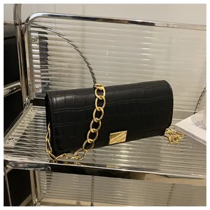 Detail of black crocodile texture handbag with gold metal clasp and chunky chain strap
