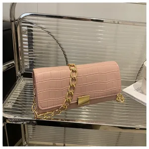 Detailed view of pink croc-textured handbag with chunky gold chain and metal buckle