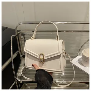 Detail of cream leather handbag with gold oval twist lock on a modern glass cart