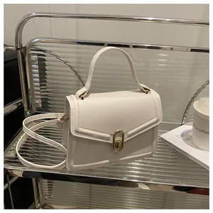 Detailed side view of cream leather crossbody bag with gold oval twist lock closure