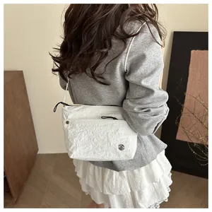 Detalle de bolso bandolera de nailon blanco con logo M metálico en conjunto casual