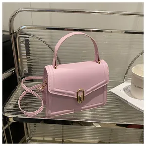 Detail of light pink crossbody bag with a gold oval metal lock and top handle