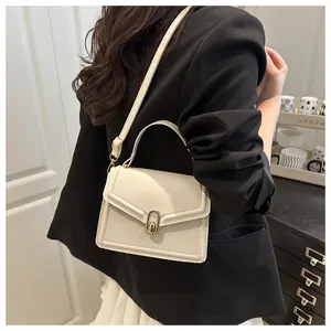 Model wearing a beige crossbody bag with gold lock and black blazer in lifestyle setting