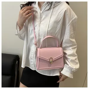 Pink leather handbag with gold twist lock buckle worn by a model in casual attire