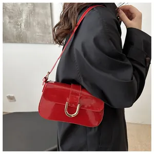Detail of red patent leather handbag with gold U-shaped buckle on black coat