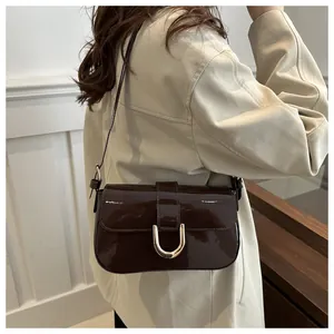 Close-up of deep brown patent leather bag featuring a glossy finish and gold U-shaped buckle