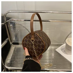 Close-up of a mini round monogram bag with brown leather handle and gold chain strap
